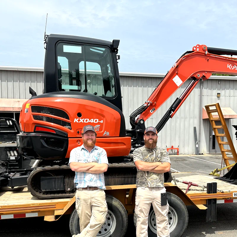 two people posing for a photo while leaning against an excavator